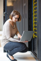 Attractive brunette adult female employee working in internet server room