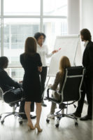 Black team leader teaching diverse business people at group meeting
